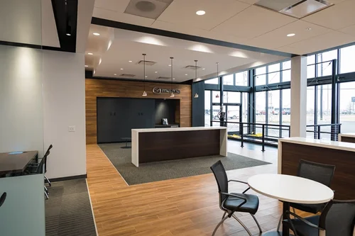 Modern Mazda dealership interior with a sleek reception desk, wood paneling, and large windows revealing an outdoor lot.